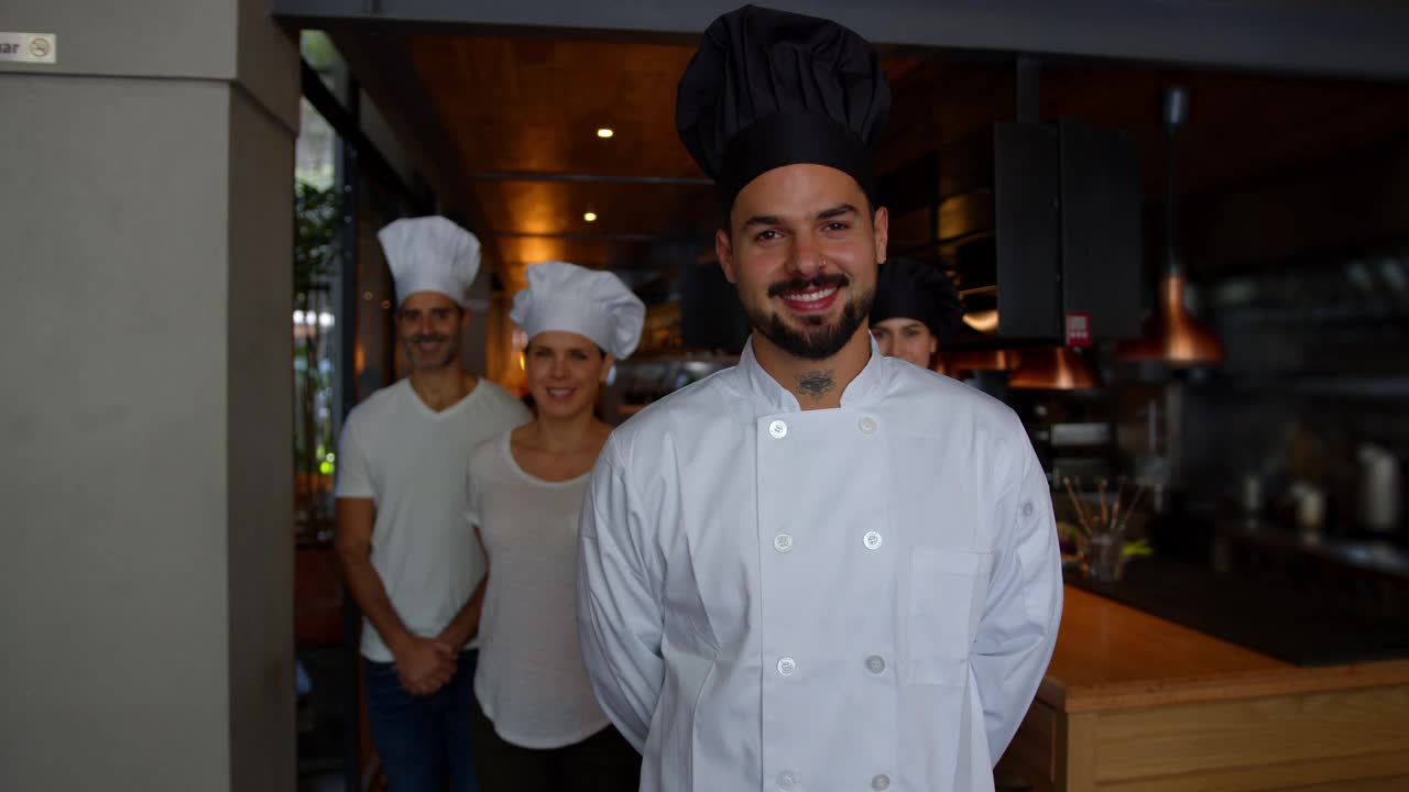 餐厅里，主厨和他的厨房员工站在镜头后面微笑视频素材