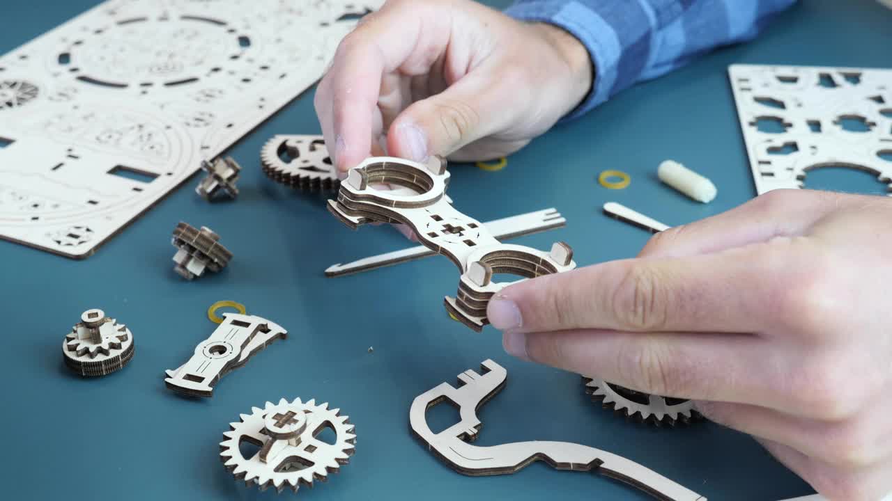 人组装机械木制玩具，手里拿着小细节。齿轮玩具。游戏概念视频下载