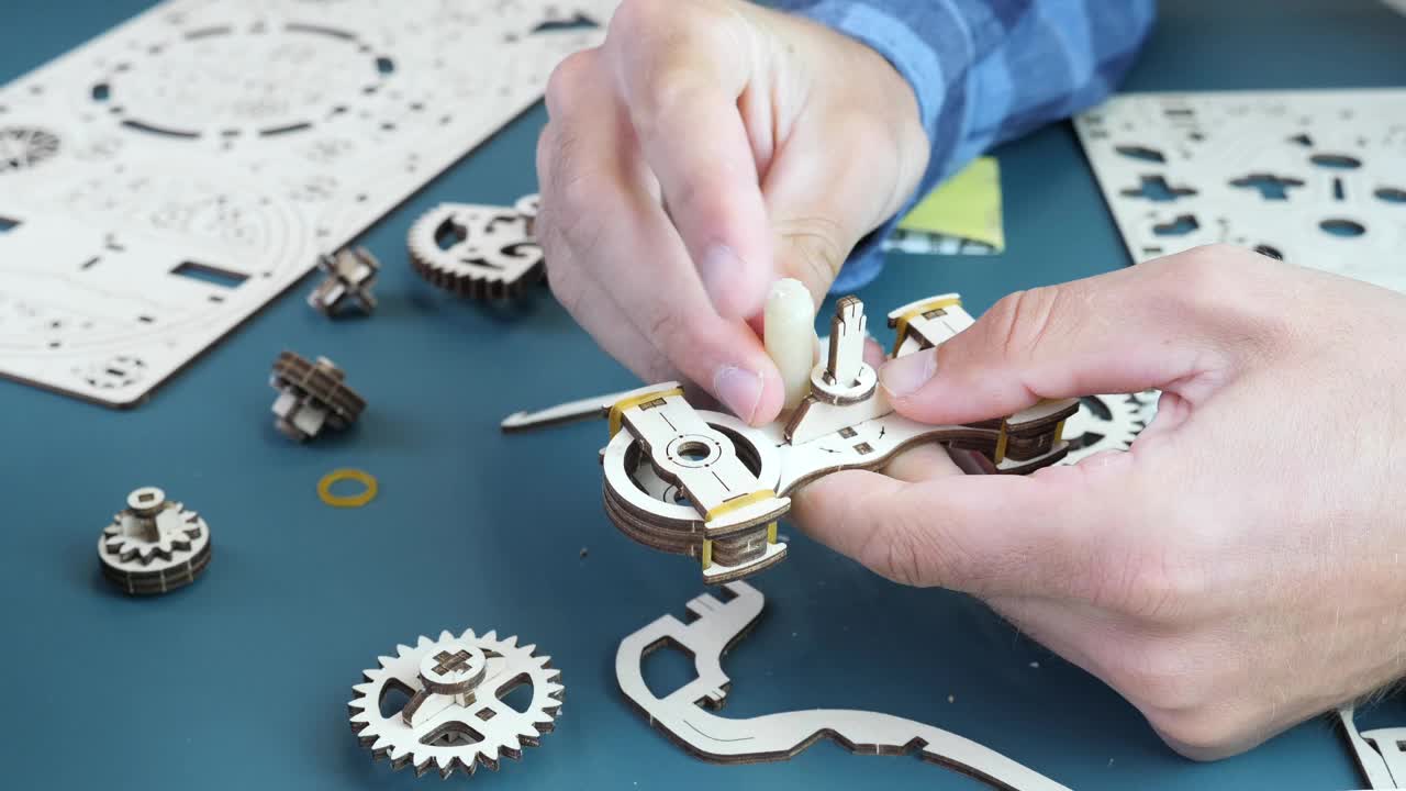 机械木制拼图玩具。男人在家里组装拼图玩具，手里拿着小的木头细节，用砂纸。休闲活动和游戏概念视频下载