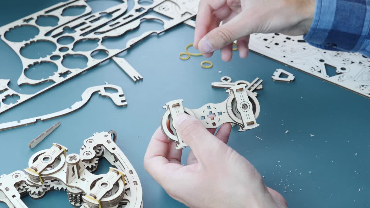 男人组装木制齿轮拼图玩具。特写男手拿小玩具的细节。机械的木制玩具。游戏活动视频下载