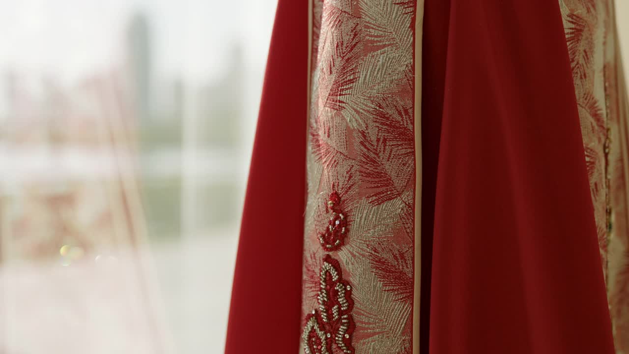年轻的中国妇女穿着传统的婚纱，红色的秀和服装，拿着中国传统的扇子，对着镜头微笑，慢镜头拍摄视频下载