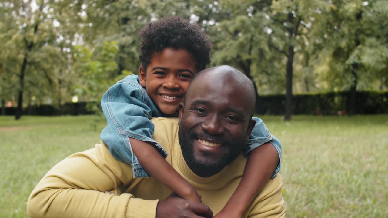 公园里微笑的美国黑人儿子和爸爸的肖像视频素材