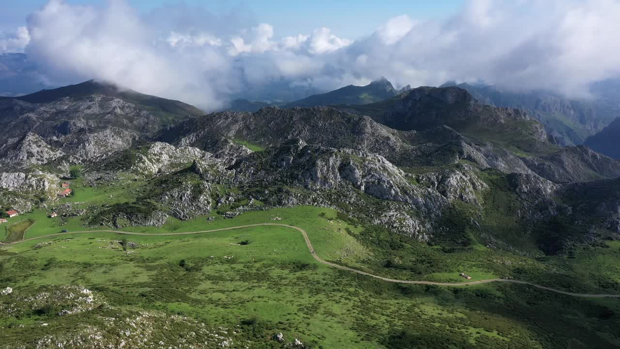 西班牙阿斯图里亚斯的拉戈斯德科瓦东加(Lagos de Covadonga)附近，阳光明媚的夏日，皮科斯德欧罗巴国家公园(Picos de Europa National Park)，俯瞰道路、绿色草地和岩石山脉的鸟瞰图视频下载