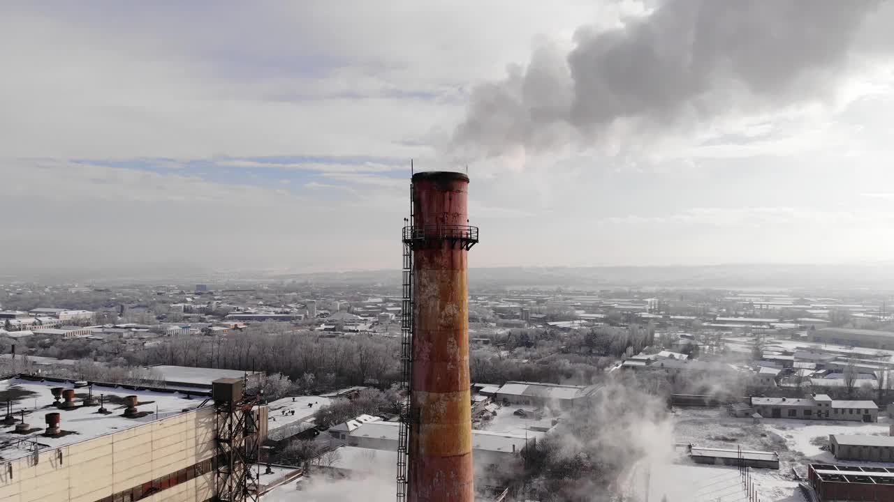 一根喷出白色烟雾的烟斗。城市燃气锅炉房的管道在冬日的天空下冒出白色的烟雾。空中特写镜头视频素材