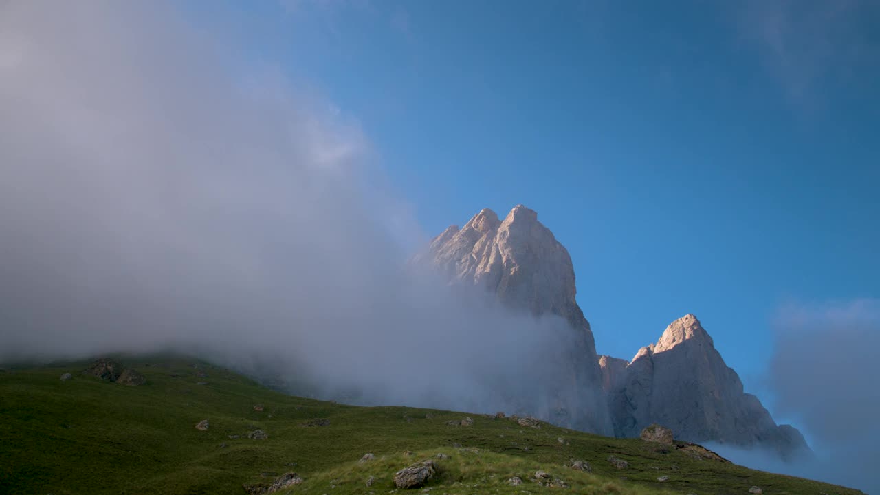 日落前的傍晚，岩石山的云朵被绿草包围的广阔动态范围的全景。来自原始视频的紧张帧视频素材