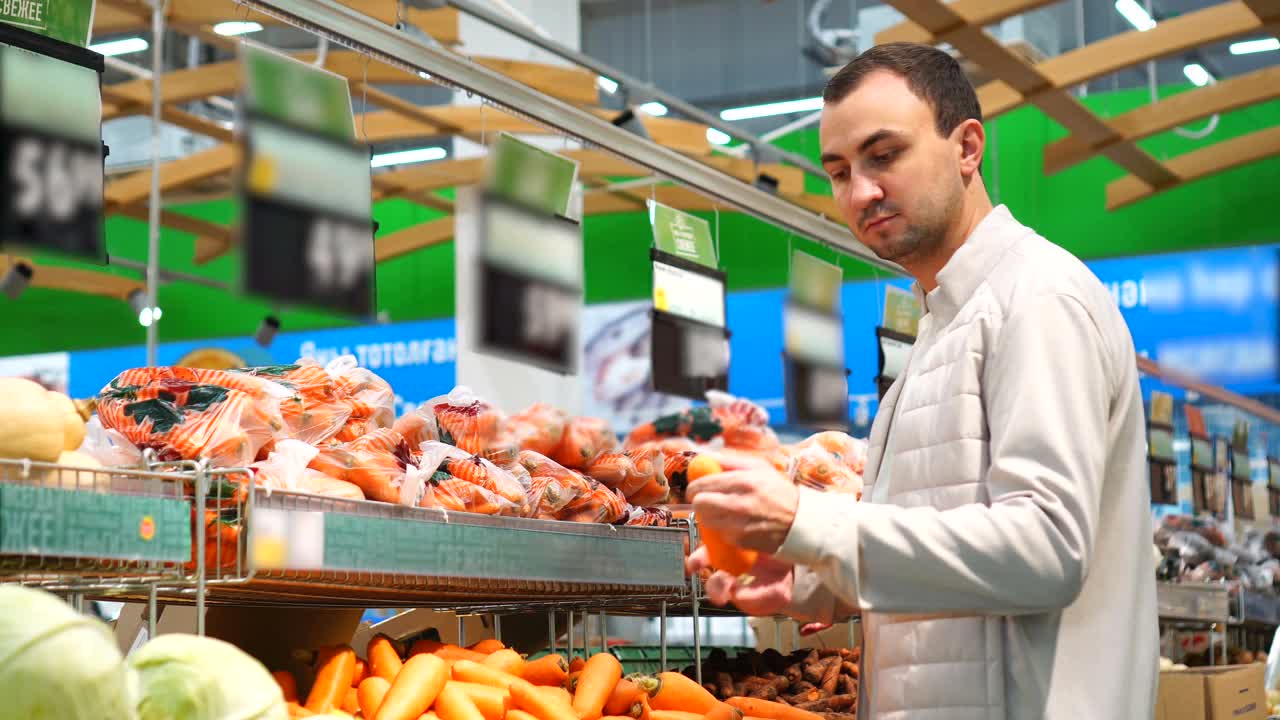 年轻人在超市挑选胡萝卜。视频下载