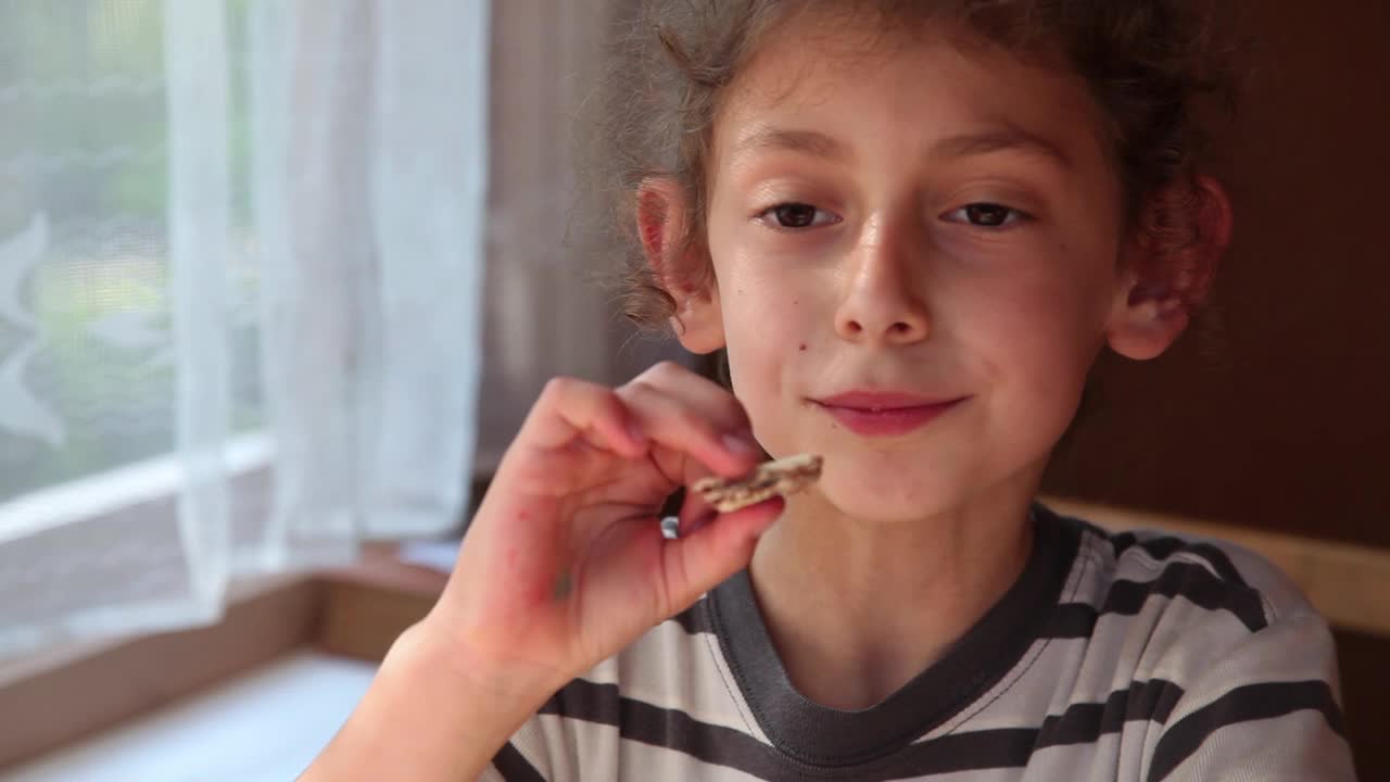 一个微笑的小女孩在靠窗的餐桌上吃甜点的特写镜头视频下载