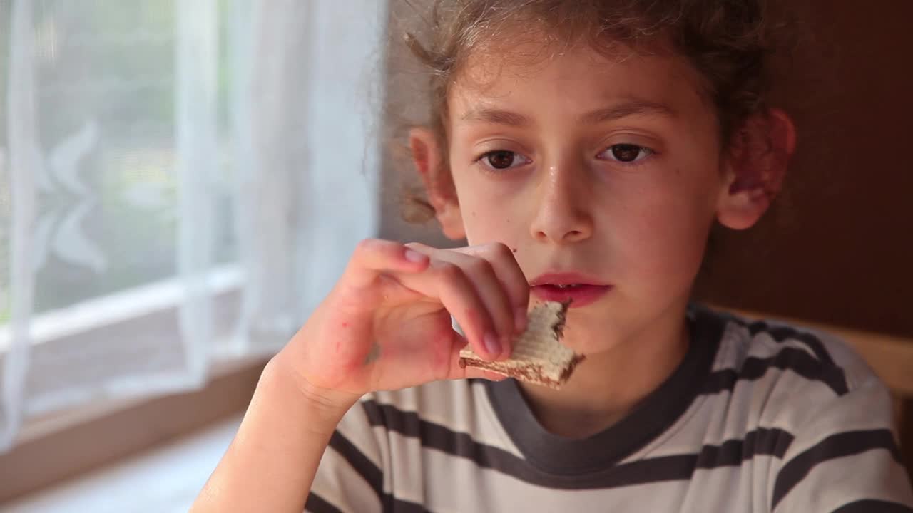 一个快乐的小女孩在餐桌上吃巧克力华夫饼的特写镜头视频下载