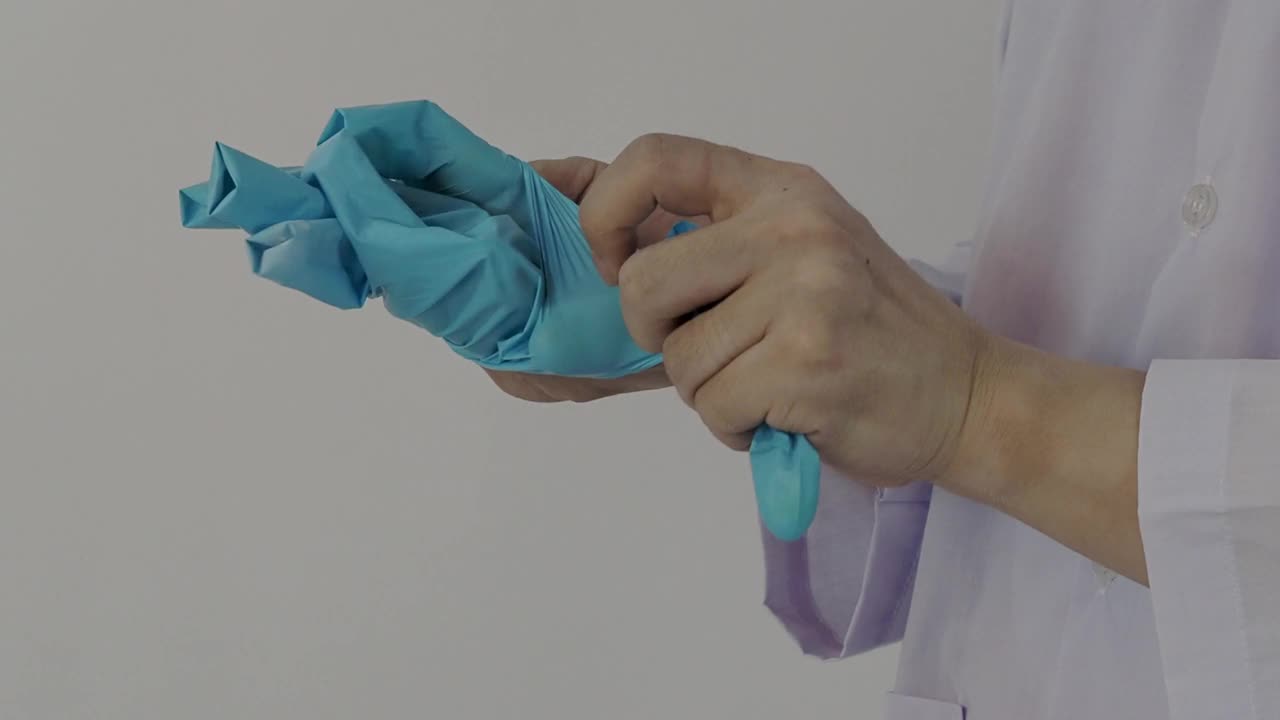 戴手套。男医生戴蓝色橡胶丁腈手套。医生戴手套的视频。孤立的白色背景复制空间。保健保护冠状病毒大流行概念。视频素材