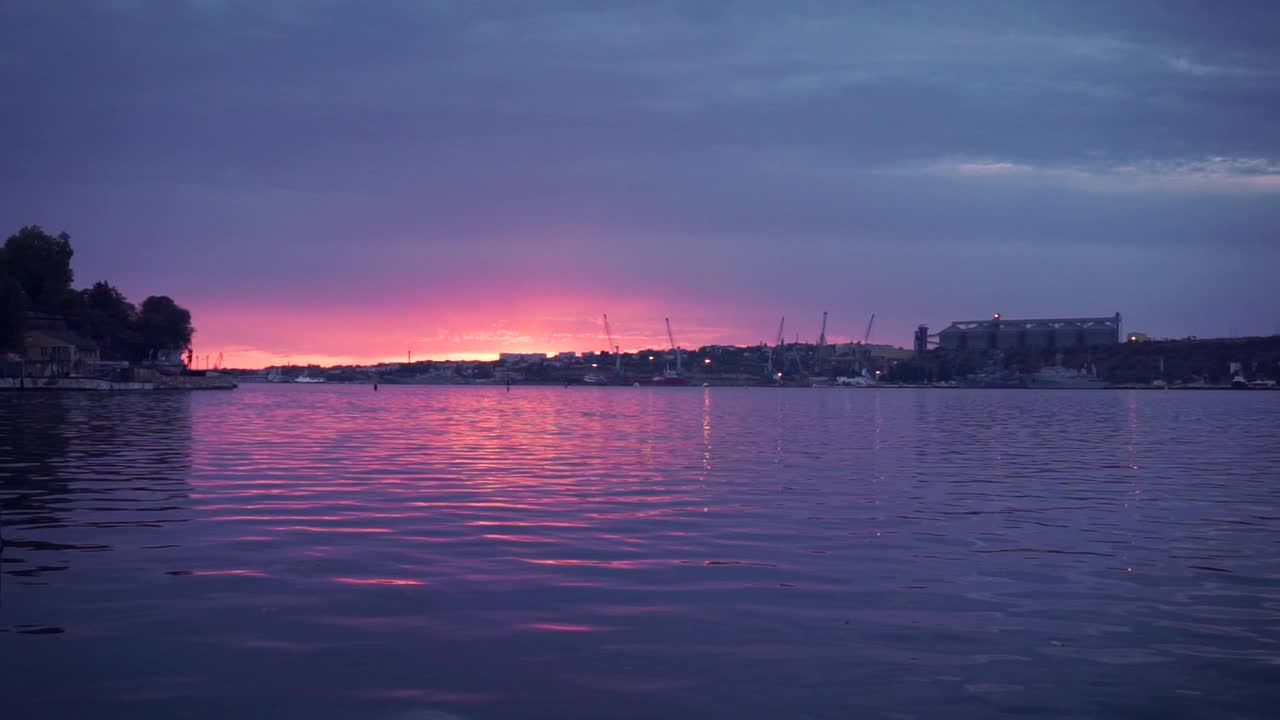 来自意大利西西里岛的美丽日落。镜头。美丽的海景，紫色和红色的天空，背景是工业港口。视频下载