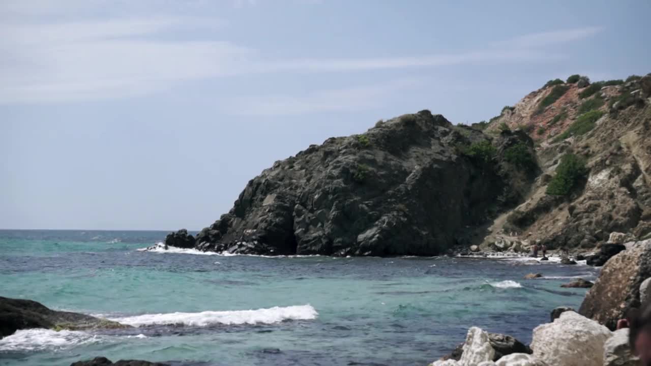 海水溅在海里的岩石上。镜头。蓝色的波浪与白色的泡沫击中美丽的石崖的希腊黑山伟大的风景。视频下载