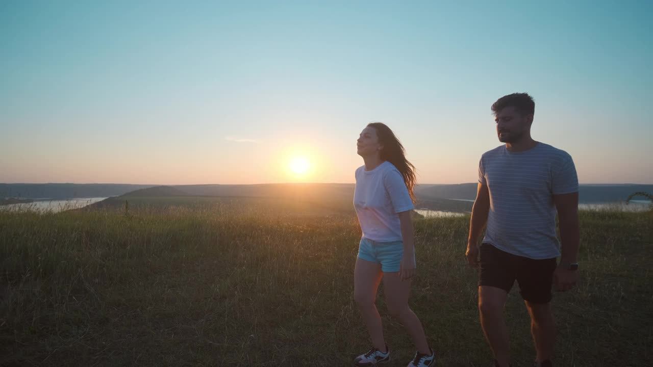 这对年轻夫妇在美丽的日落背景下玩得很开心。慢动作视频素材