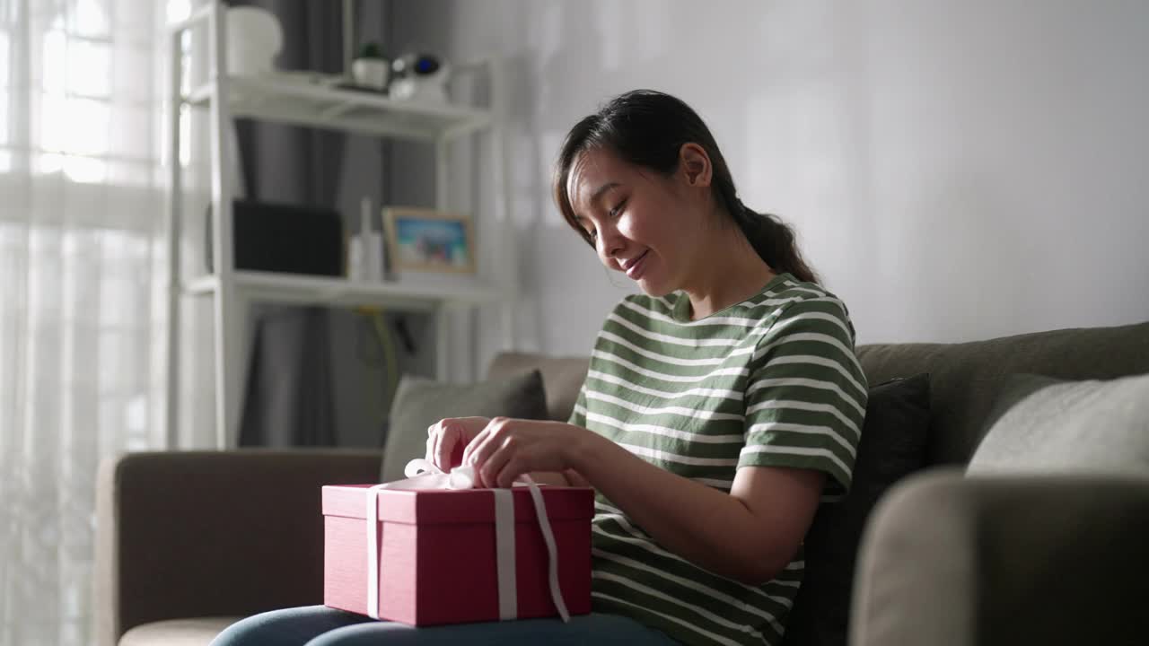 快乐的亚洲女人在家里打开礼品盒视频素材