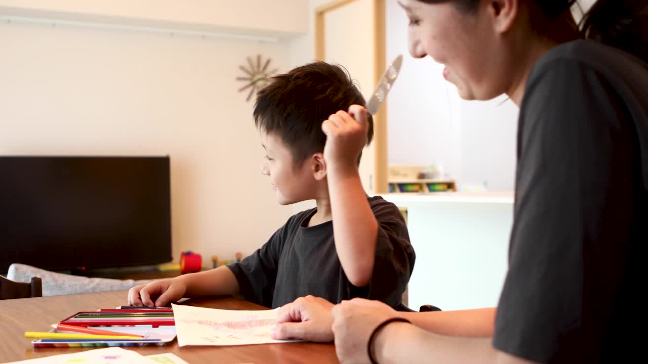 一位母亲和她五岁的儿子在一起玩彩色铅笔视频素材