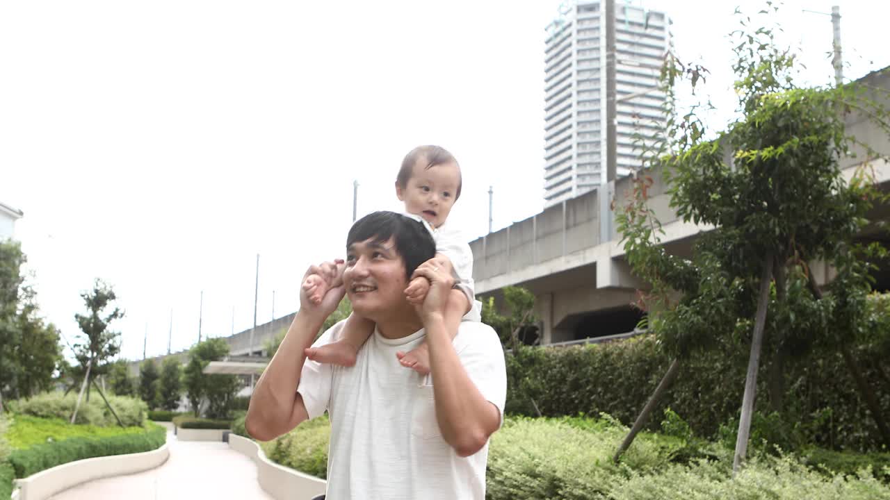 一位父亲和他一岁的儿子在肩背上玩耍视频素材