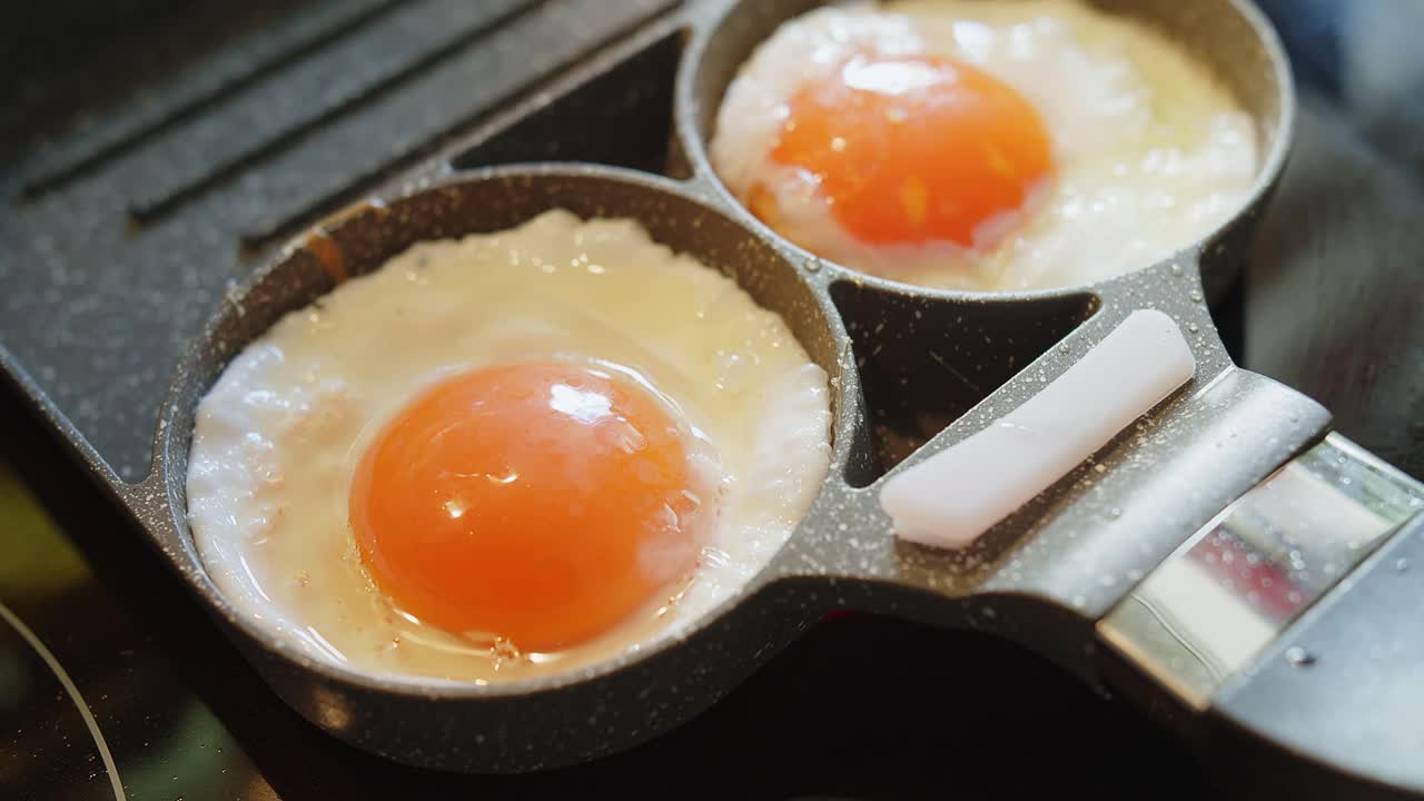 近距离烹制新鲜煎蛋蛋黄和蛋白热锅滋，简单美味美味的早餐食物视频素材