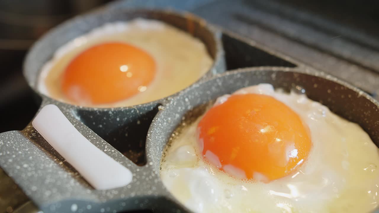 近距离烹制新鲜煎蛋蛋黄和蛋白热锅滋，简单美味美味的早餐食物视频素材