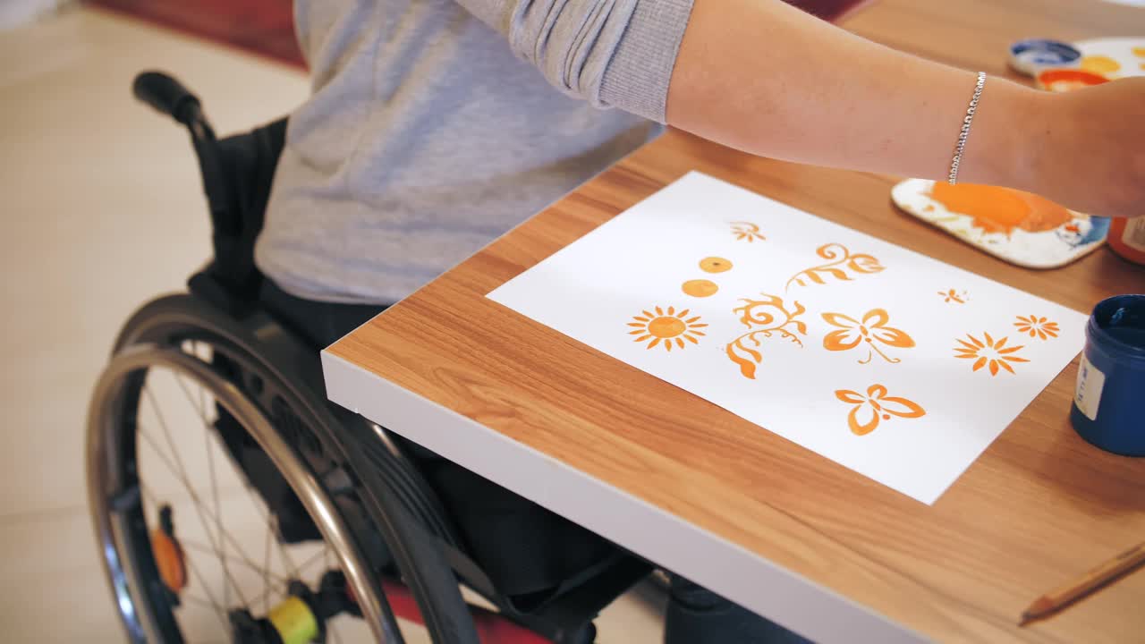 轮椅。残疾。特写镜头。残疾的年轻女子坐在轮椅上画画。为残疾人提供创造性课程。教育、关系与人文观念视频素材