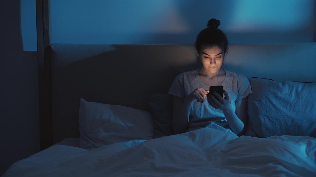 晚上失眠手机成瘾的女人卧室视频素材