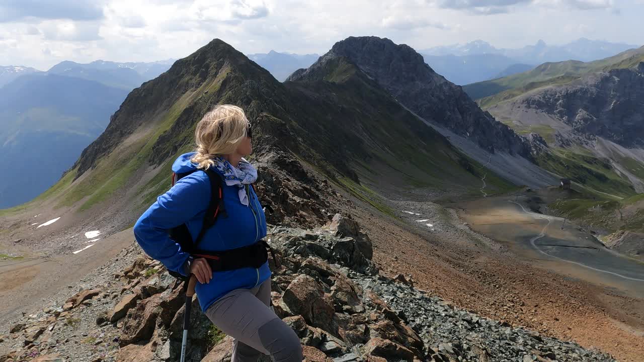 一位女性徒步者爬上阳光明媚的山脊视频素材