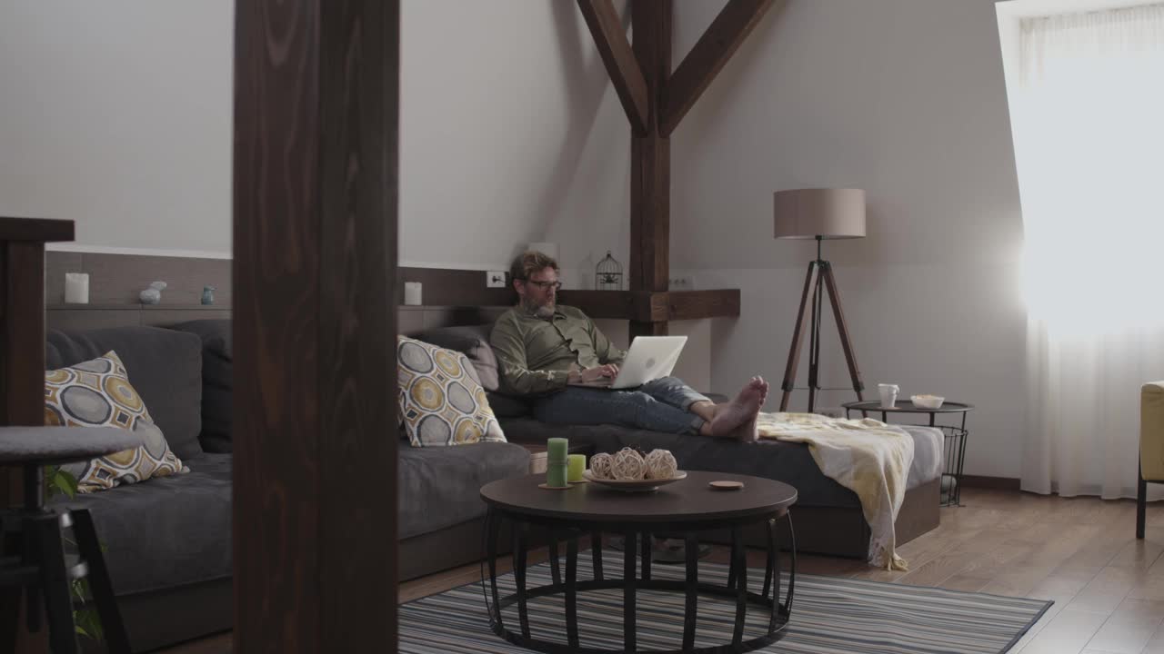 一个成熟的男人在他舒适的客厅沙发上工作视频下载