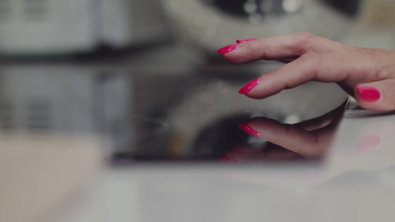 女人按下感应炉顶部的按钮来设定烹饪菜肴的温度视频下载