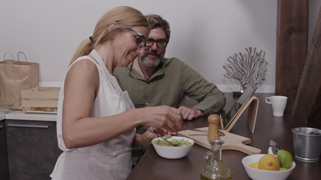 一个男人和他的妻子在他们准备的鳄梨酱中加入柠檬汁和橄榄油视频下载