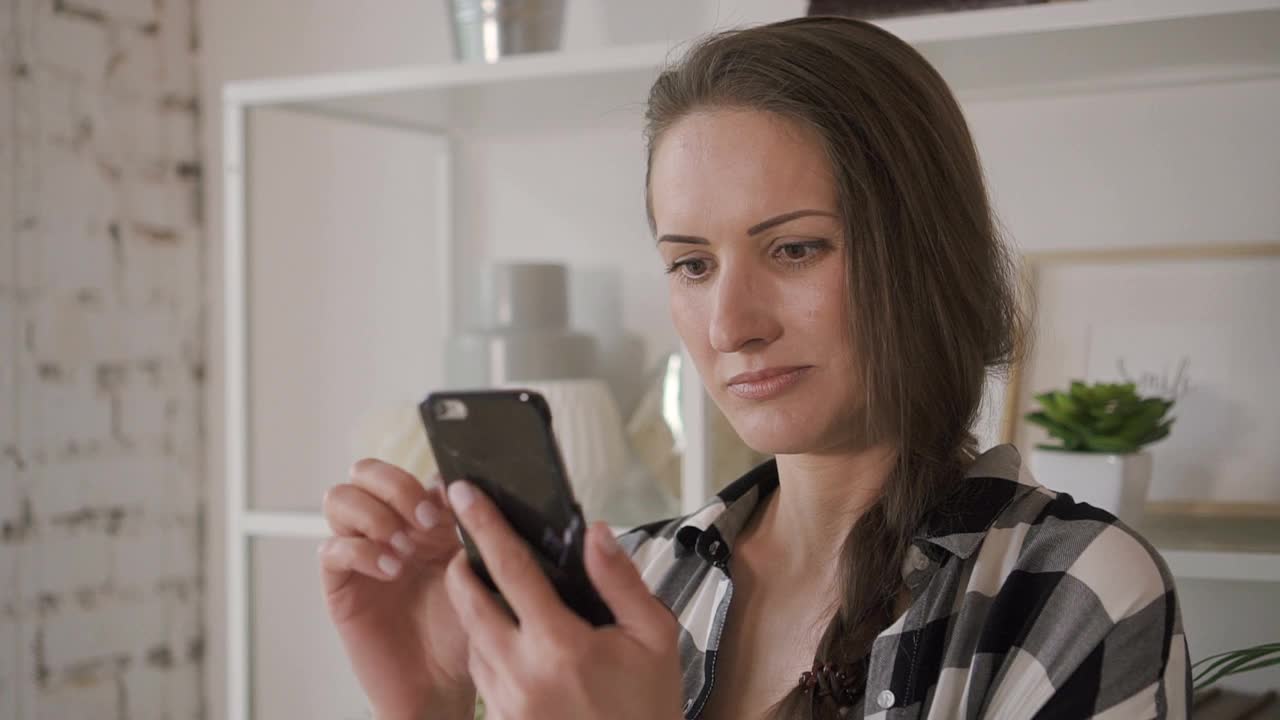 欧洲女性在家庭办公室看社交媒体，拿着手机视频下载