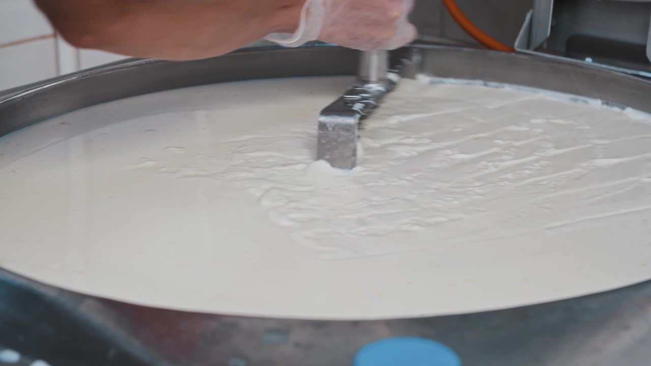 奶酪工厂工人用一把大剃刀在大桶里切割柔软的新鲜奶酪视频素材
