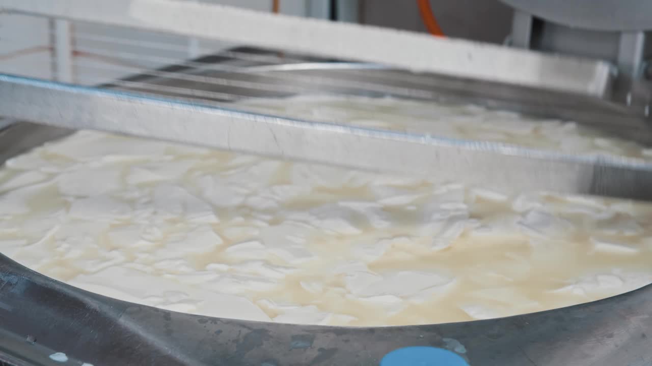 奶酪工厂工人用一把大剃刀在大桶里把柔软的新鲜奶酪切成小块视频素材