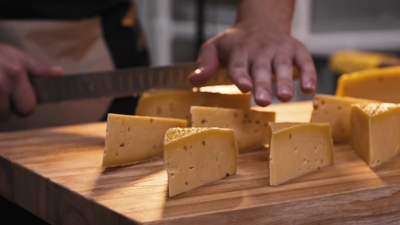 一个男人在商店里用刀把一个巨大的奶酪头切成三角形视频素材