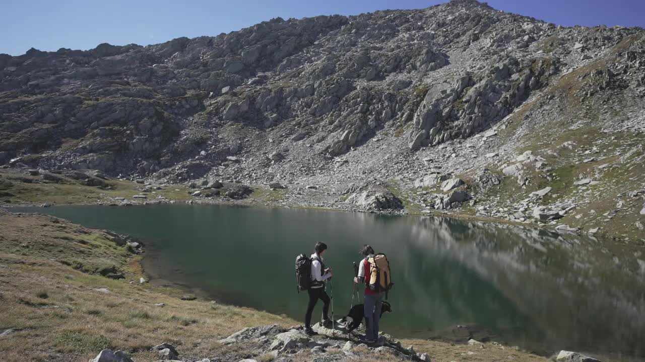 一男一女带着一只狗站在山间的湖边视频素材