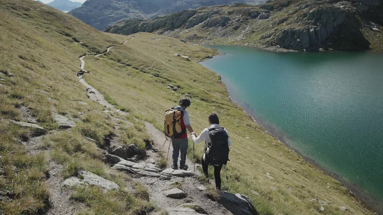 一男一女在山上的湖上徒步旅行的广角镜头视频素材