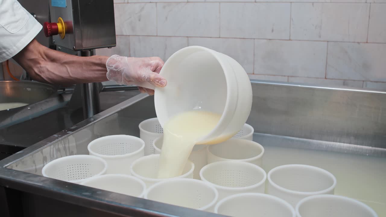 戴手套的奶酪工厂工人用滤锅过滤带有软奶酪的液体视频素材