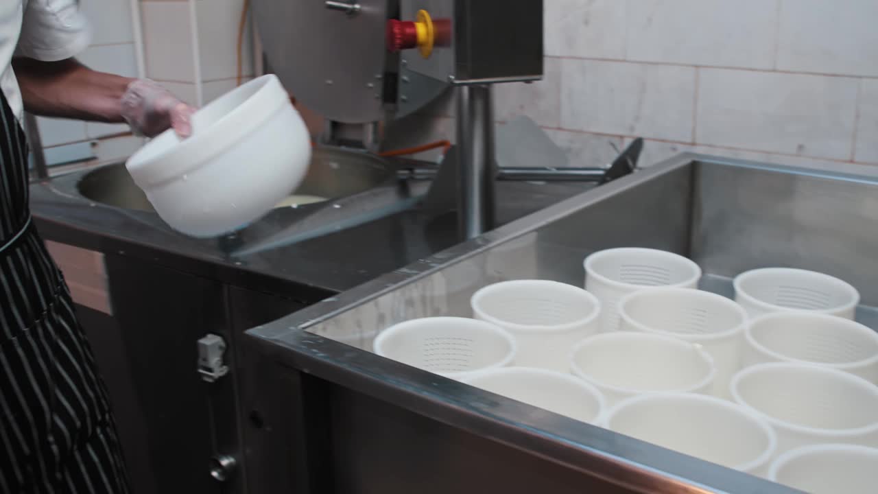 乳酪制造厂-戴手套的工人用滤锅过滤带有软乳酪的液体视频素材
