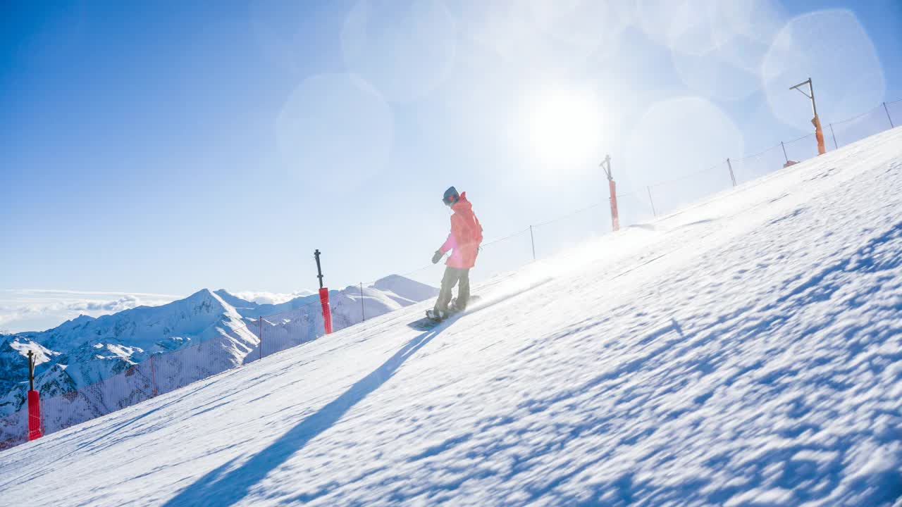 滑雪板运动员在滑雪道上滑行，在转弯时喷着雪，背景是山脉视频素材