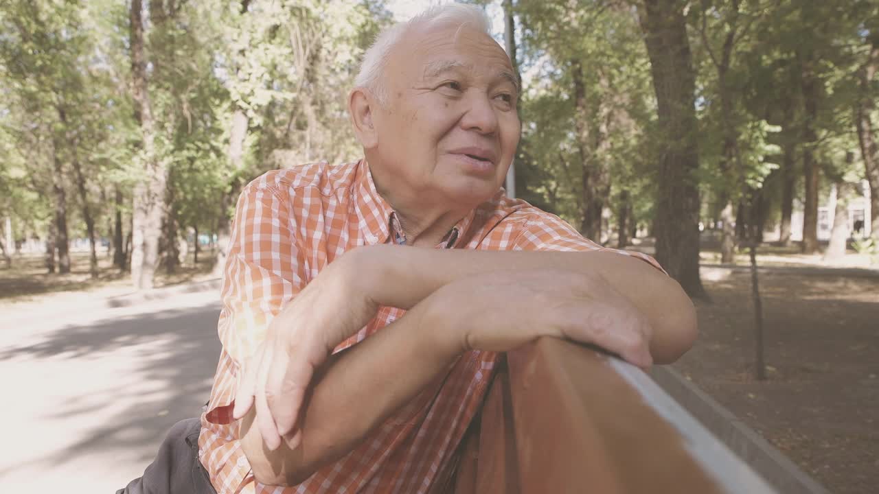 一个活跃的老人坐在公园的长椅上视频素材