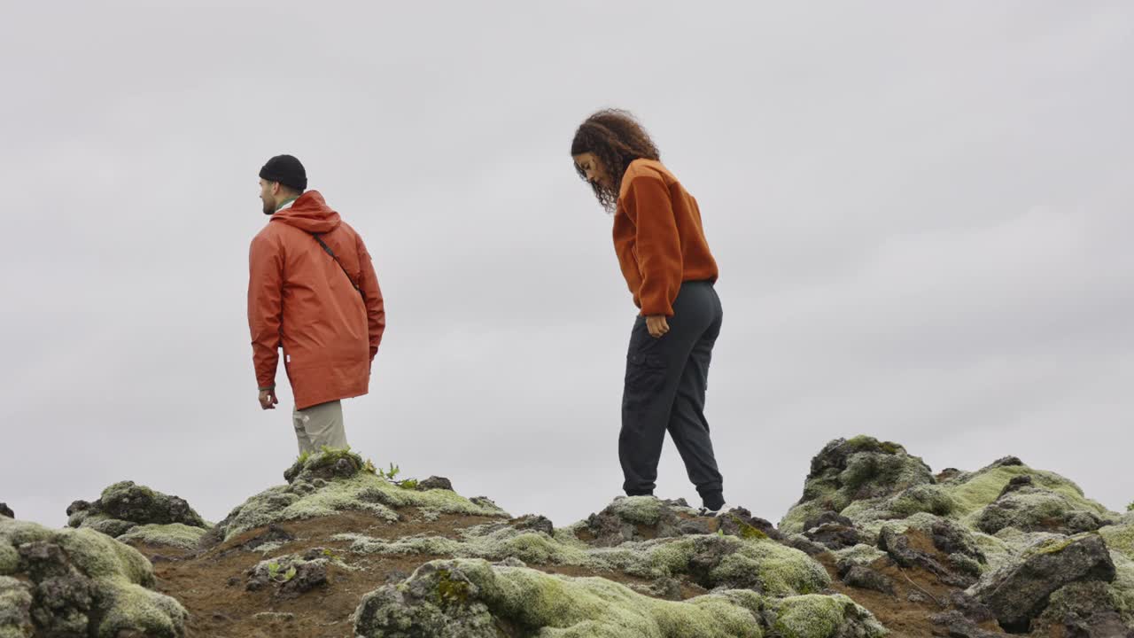 在岩石和苔藓覆盖的景观中徒步旅行的夫妇视频下载