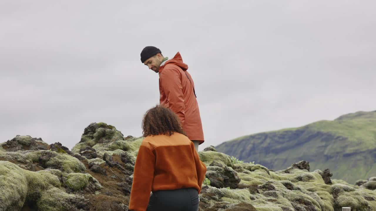 一对情侣在长满苔藓的岩石上牵手视频素材