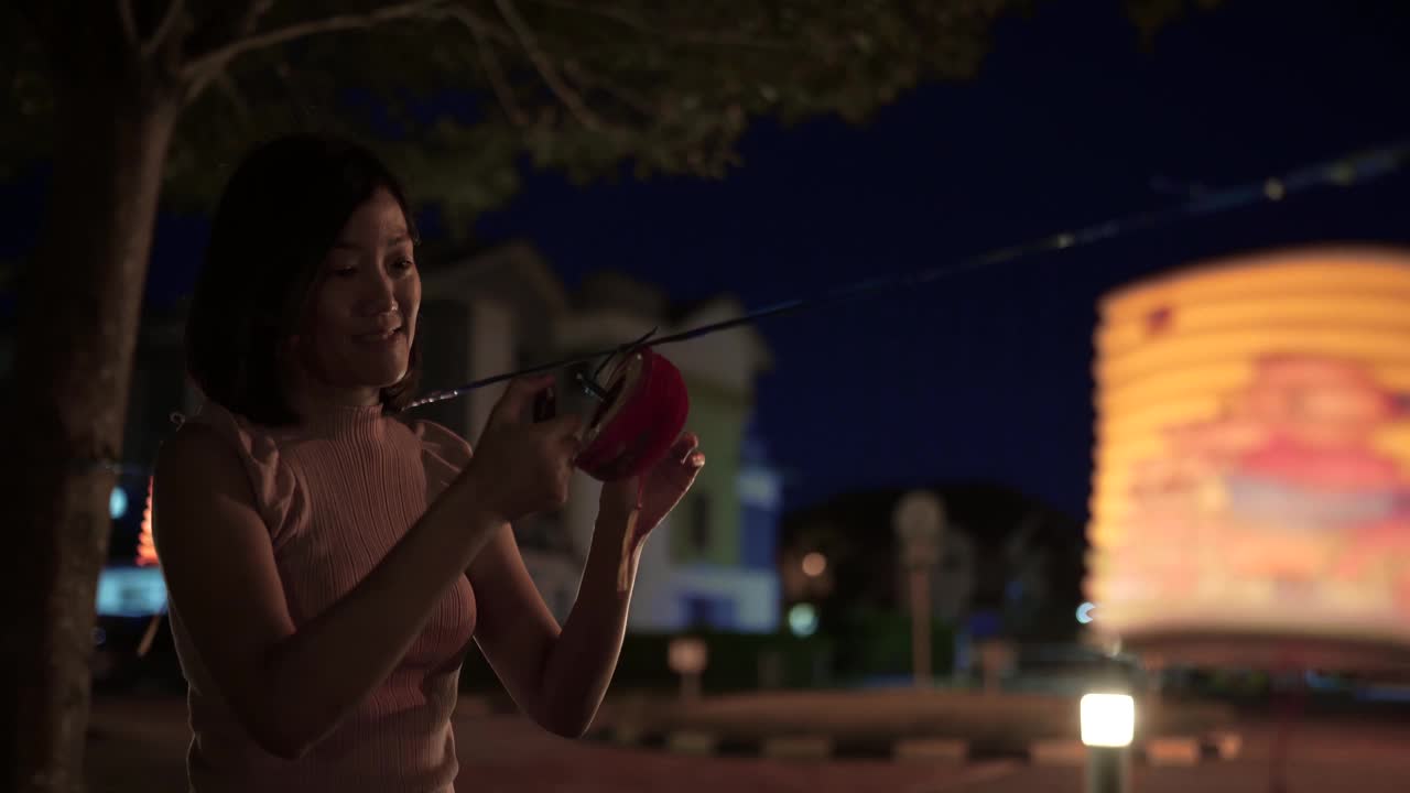亚洲华人妇女在纸灯笼里点燃蜡烛，庆祝中秋节。视频素材