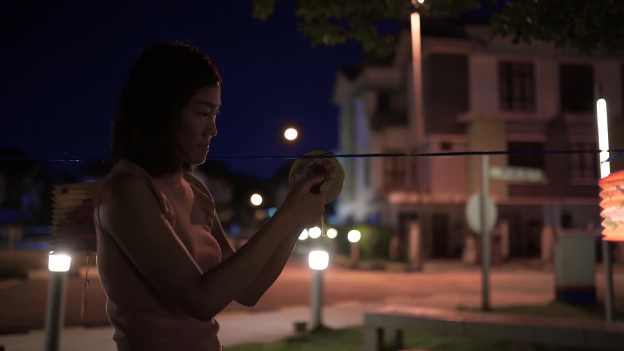 亚洲华人妇女在纸灯笼里点燃蜡烛，庆祝节。视频素材