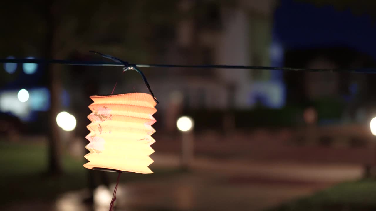 亚洲华人妇女在纸灯笼里点燃蜡烛，庆祝节。视频素材