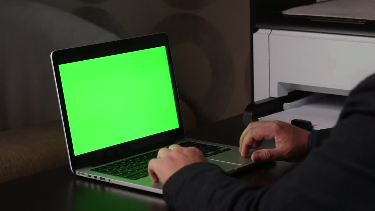 一名男子在一台绿色屏幕的笔记本电脑前工作。表示拇指向下的手势。Chromakey。视频素材
