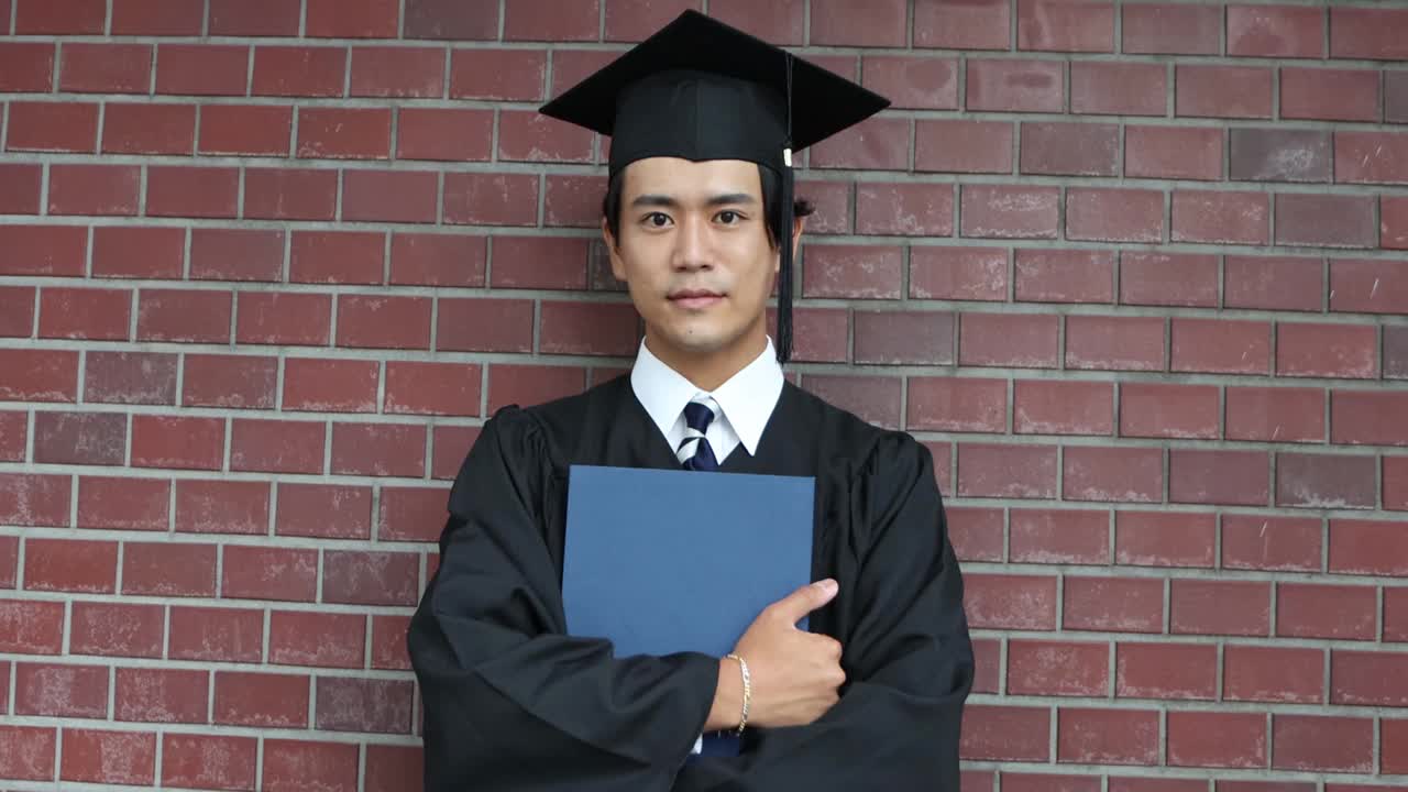 一幅亚洲学生的肖像，戴着学士帽，穿着学位服庆祝毕业视频素材