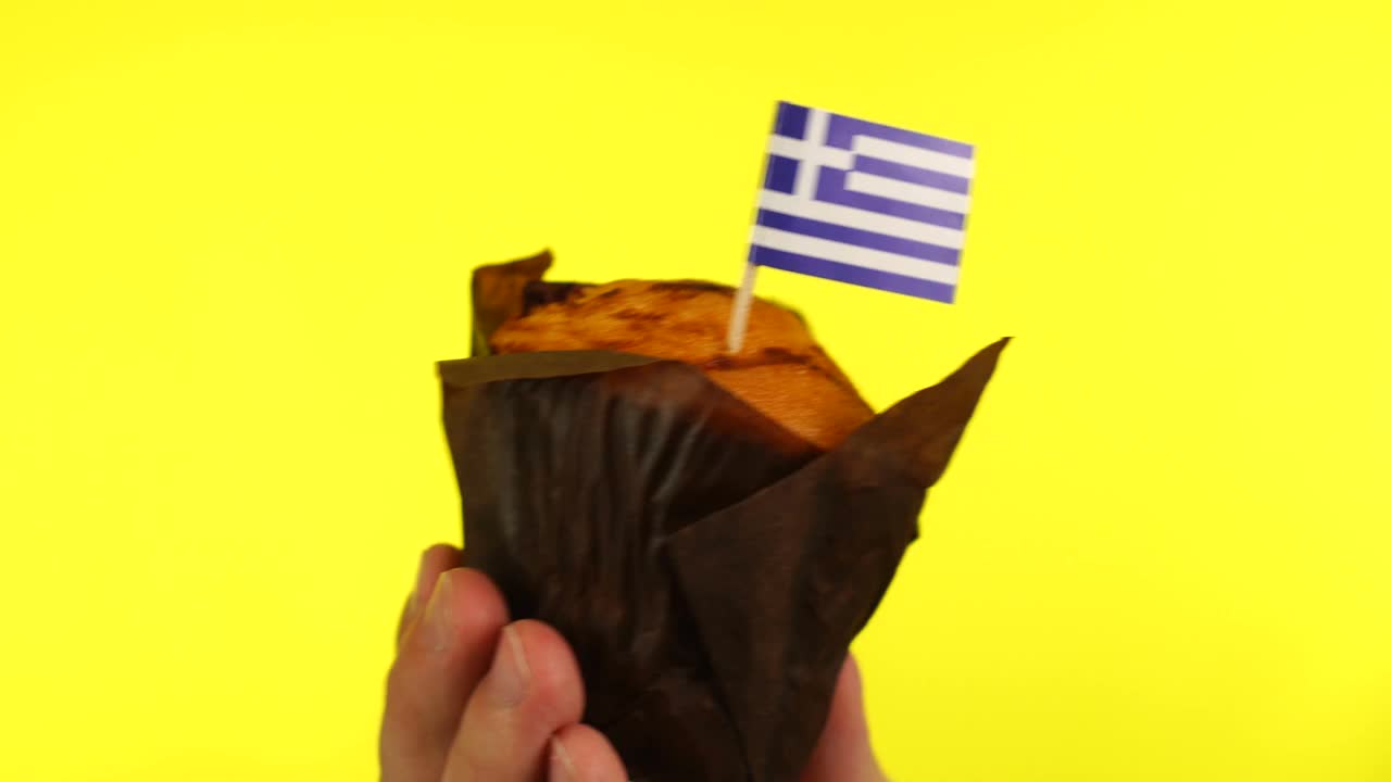 黄色背景下，男性手掌上有希腊国旗的纸杯蛋糕视频下载