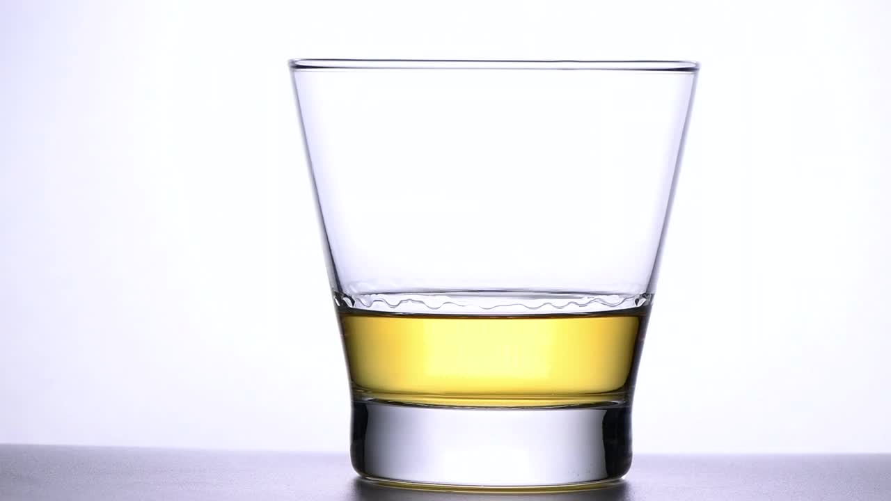 慢动作上倒冰块到威士忌孤立在白色背景，饮料和饮料的概念视频素材