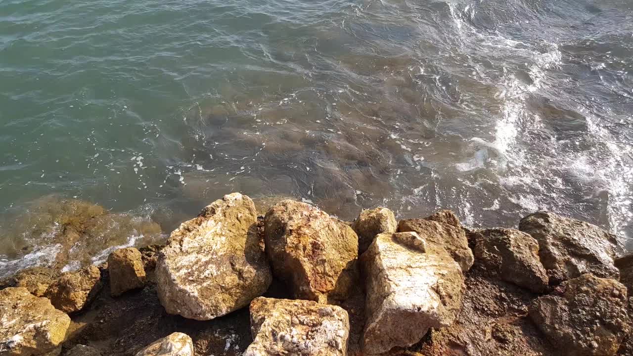 美丽的海浪和地中海多石的海岸。从上往下鸟瞰海浪撞击和泡沫。视频下载