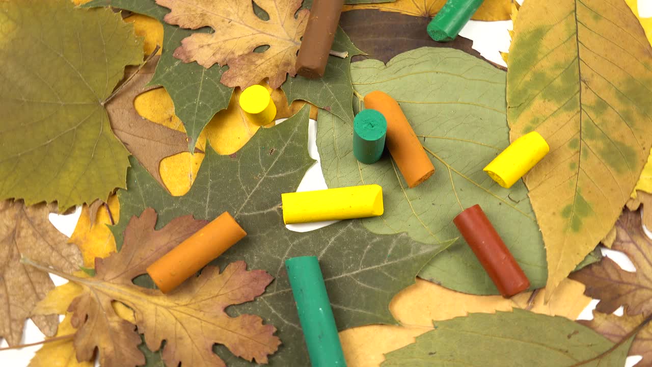 黄色，绿色和棕色的蜡笔和秋天的树叶，背景。视频素材