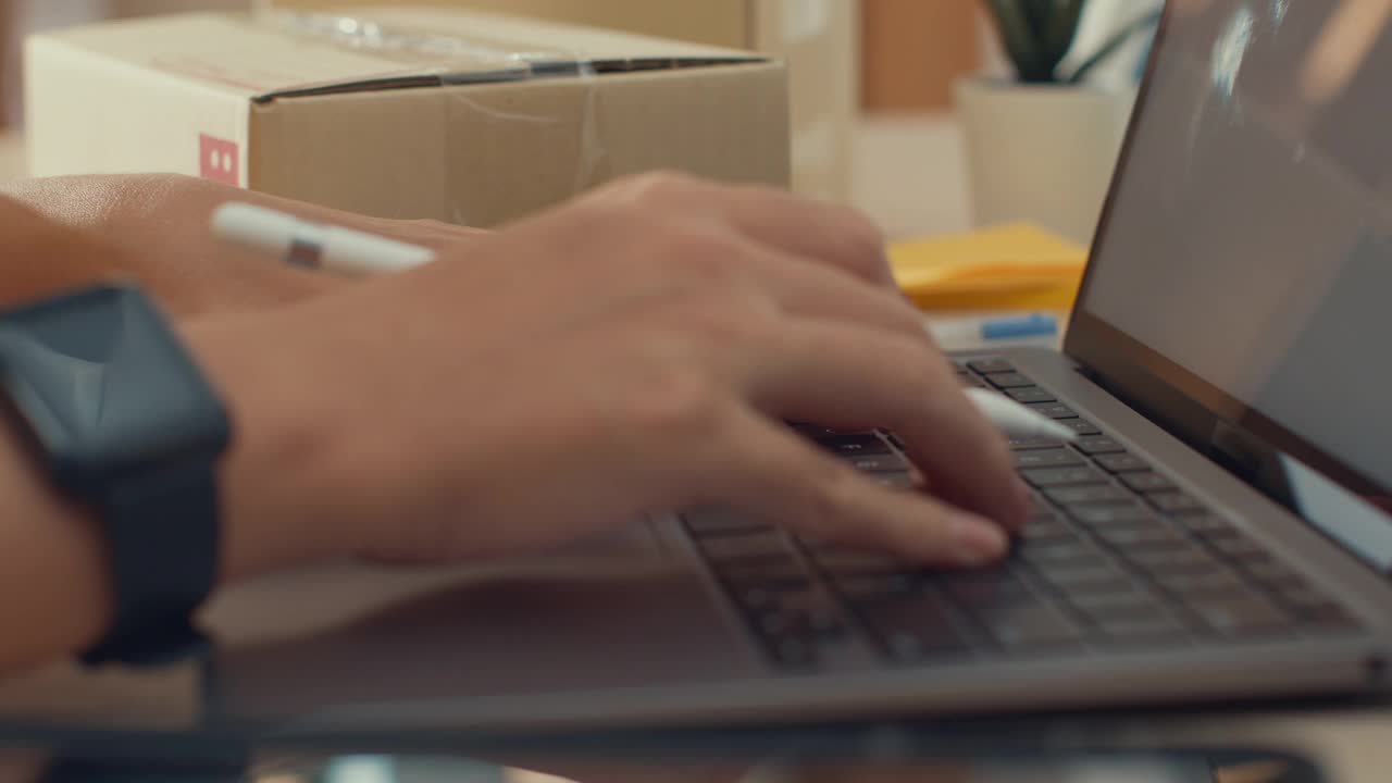 年轻的自由亚洲妇女使用笔记本电脑包装纸箱在客厅在家里。视频下载