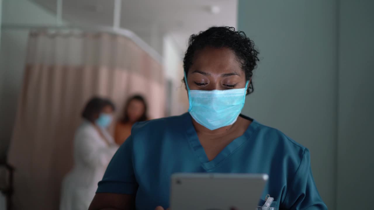 一名护士在医院使用数码平板电脑，戴着防护口罩视频素材